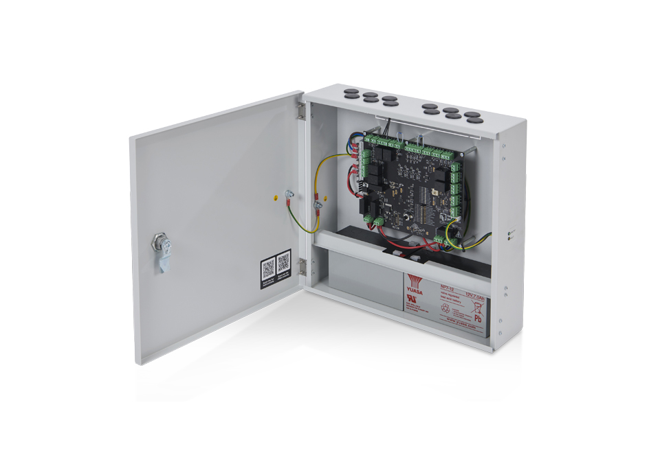 A wall-mounted electrical control box with its door open, displaying internal wiring, circuit board, and components designed for door automation. The box has multiple cable entry points at the top.